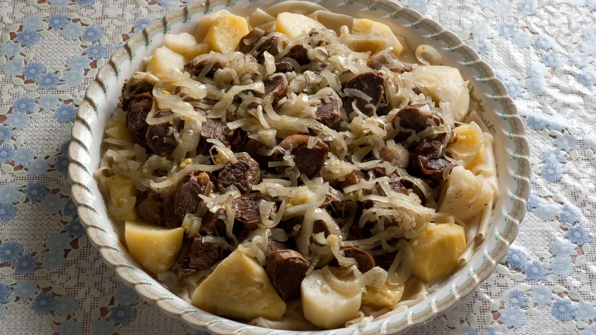 Traditional Kazakh beshbarmak dish with boiled meat and flat noodles on a large communal plate