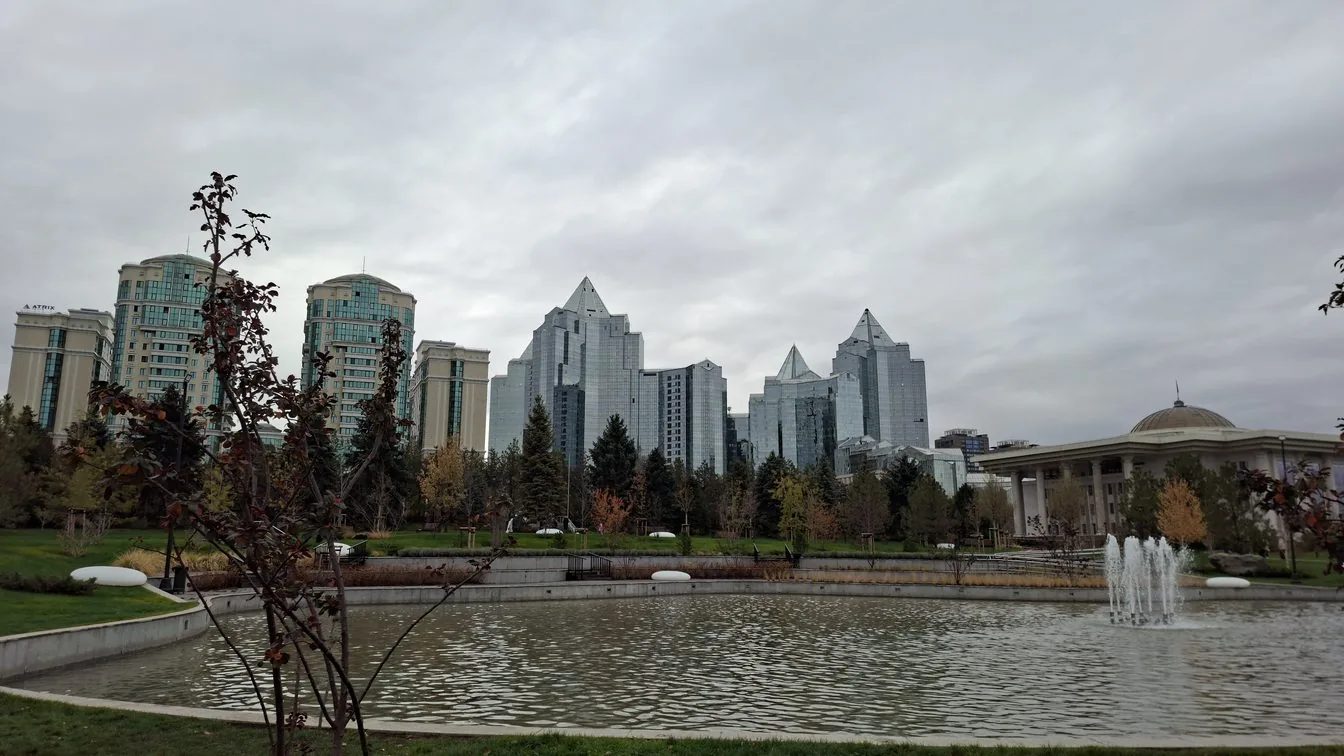 Solo female traveler walking through central Almaty with mountains visible in the distance